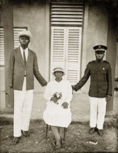 Portrait of Salvation Army workers. Two African men in Western dress stand on either side of a