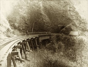 Railway bridge, Queensland. A man and young boy stand on a railway bridge cut into the side of a