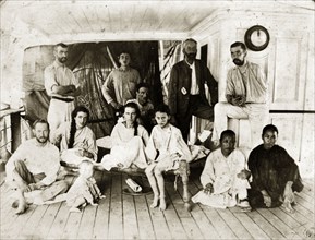 Survivors from SS Aden. Twelve men, women and children in informal dress pose on the deck of a ship