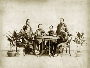 Chinese ladies playing 'fantan'. Studio portrait of six Chinese ladies playing a card game