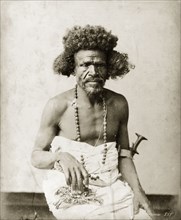 Portrait of an ageing man. The man is shown seated, with a cloth wrapped around his chest and lower