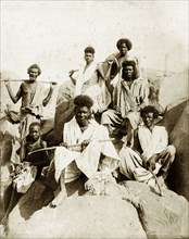 A group of Bisharin people. Group portrait of seven Bisharin people posed on boulders. Probably