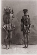 Andaman Islanders. A man and a woman from the Andaman Islands stand, backs facing the camera,