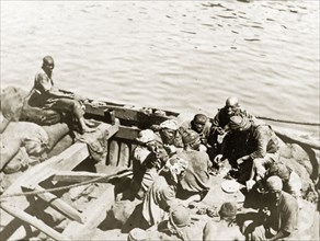 Coal workers at lunch. Several coal porters sit aboard an open wooden barge as they eat their lunch