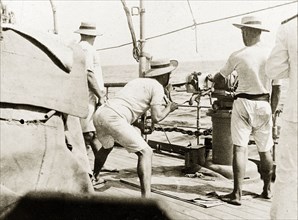 Firing a gun from RIMS 'Minto'. British naval officers fire a three pound gun on the deck of RIMS