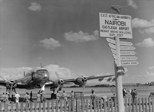 Eastleigh Airport, Nairobi. Airport staff mill around a double-propellered passenger plane that