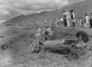 Cooper in the ditch. A Cooper racing car lies upturned in a ditch having veered off the track at