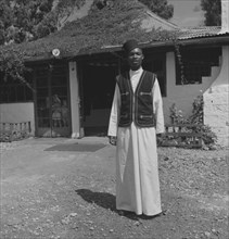 Uniformed Kenyan bartender. A uniformed Kenyan bartender poses for the camera outside a colonial