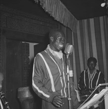 Singer at the Equator Club. An African man sings into a microphone on a small stage at the Equator