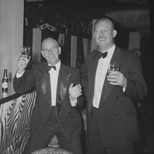 At the Equator Club, Kenya. Two European men dressed in suits raise their glasses for the camera