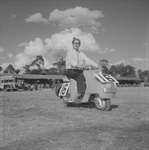 Scooter at the Royal Show. A European man sits on scooter number 16 in a vehicle parade at the