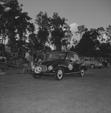 DKW in a vehicle parade. A man drives a DKW car past a crowd of onlookers during a vehicle parade