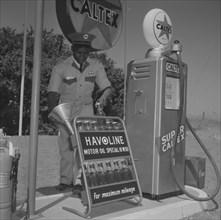Havoline at Caltex. A uniformed attendant holds a funnel in one hand and a bottle of 'Havoline