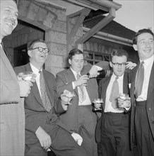 Champagne top-up. Five male wedding guests dressed in suits enjoy a champagne top-up at the