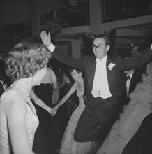 Quirky dancing. An excited man demonstrates a quirky move to his dance partner, arms outspread, at