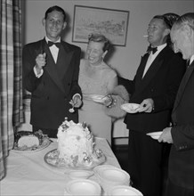 Cutting the cake. A young man dressed in a tuxedo, holds up a knife for the camera before cutting