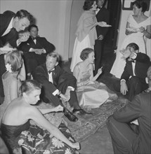Animated socialising. A group of animated young men and women dressed in formal attire socialise at