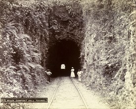 Extension from Porus to Montego Bay. A woman and two men stand at the entrance to a railway tunnel