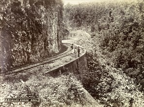 Railway track at Bonas Rock. Three men stand on a stretch of railway track that clings to the side