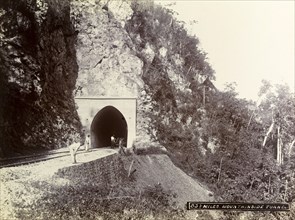 Mountainside tunnel, Jamaica. Three men stand at the entrance to a railway tunnel cut into the side
