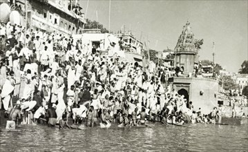 Religious pilgrims at Benares. Religious pilgrims crowd the steps of a bathing ghat (stepped wharf)