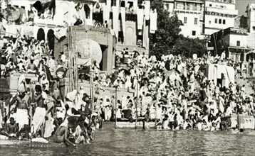 Religious pilgrims at Benares. Religious pilgrims crowd the steps of a bathing ghat (stepped wharf)