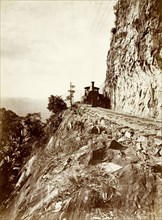 Steam train at 'Sensation Rock'. A steam locomotive rounds the corner of a mountain at 'Sensation