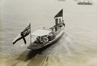Royal barge at Bombay. A small barge decorated with flags ferries King George V (r.1910-36) and