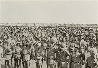 Three cheers for King George V. Numerous lines of uniformed soldiers stretch into the distance,