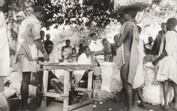 Cotton marketing at Meridi. Traders queue at an open-air market, balancing large, open-weave