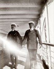 Officers aboard the S.S. Balmoral Castle. Two British naval officers hold hands and pull faces for
