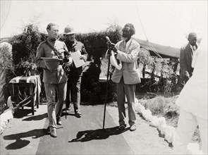 Entrance to a Presentation of Address. An African man, dressed in a Western-style suit, adjusts a