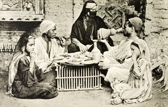 A familiar dinner'. A posed portrait depicting a 'typical' Egyptian meal. A veiled woman adorned