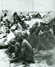 Ethiopian slave market. Male slaves sit on the ground in groups outside makeshift tents at an