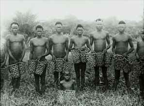 Congolese rubber slaves. A group of male slaves pose, holding empty baskets, as they prepare to
