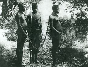 Congo Free State hostages. Two semi-naked women are chained together by the neck under armed guard.