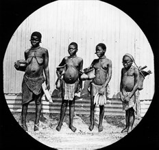 Four African women. Group portrait of four semi-naked women, each carrying a basket filled with