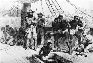 Boarding a slave ship. African slaves are mannacled and shackled by European slave traders as they