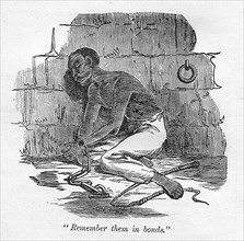 Remember them in bonds'. A slave with bound hands is chained to the floor of a cell, kneeling