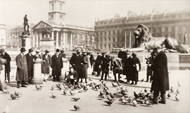 Feeding the pigeons. A crowd of people feed the pigeons in Trafalgar Square. London, England, circa