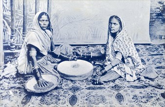 Indian women grinding corn. A posed portrait of two Indian women grinding corn between a pair of