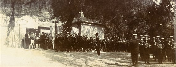 Military march in Gibraltar. A military regiment marches past a gateway, their bayonets resting on