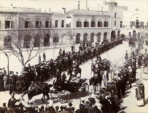 Procession in Gibraltar. Two distinguished gentlemen are driven through crowds gathered in a town