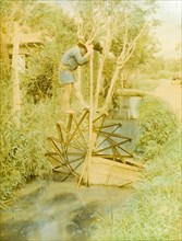 Japanese water wheel. A Japanese man treads the paddles of a wooden water wheel as he raises water
