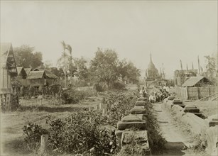 Wuntho after its capture. A pathway flanked by low walls leads past a number of thatched dwellings