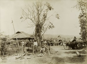 Soldiers visit a Burmese village. British and Indian soldiers visit a Burmese village. Possibly a