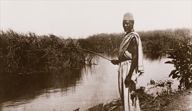 Fishing in the Jur River. A man stands fishing on the bank of the Jur River, holding a fishing rod