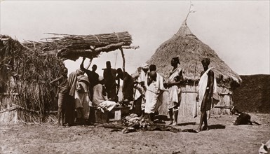 Butcher's shop in a Sudanese village. A line of men queue up outside a village butcher's stall,
