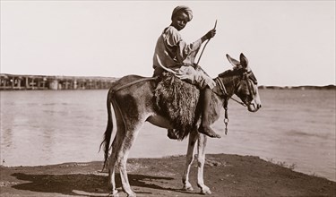 Sudanese boy on a donkey. Portrait of a Sudanese boy, sitting astride a harnessed donkey beside a