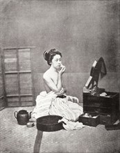 Japanese woman applying make-up. A photograph printed in 'The Sketch' newspaper features a young